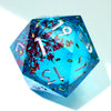 A translucent blue resin D20 die with a liquid swirl featuring red and purple floral elements.