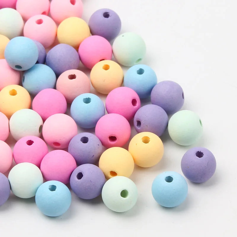 A collection of matte acrylic beads in various pastel colors including pink, purple, yellow, and blue.