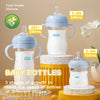 A set of three stages of silicone baby bottles for infants, including a large bottle and smaller ones, displayed on a yellow 