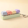 A colorful acrylic fidget keychain featuring four clicky key buttons in pastel shades.