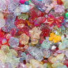A close-up of colorful butterfly shell acrylic beads in various shades of pink, purple, green, and orange.
