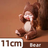 A small brown bear-themed reborn baby doll with closed eyes and tiny hands sitting on a wooden surface.