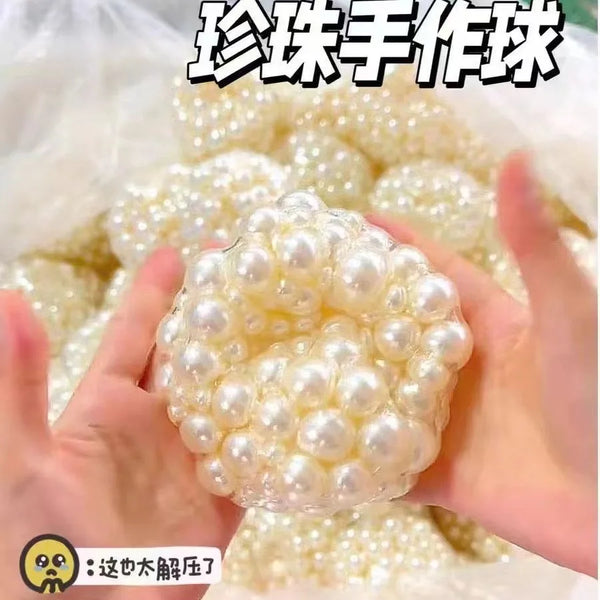 Hands holding a white pearl bead stress relief squishy ball surrounded by other beads