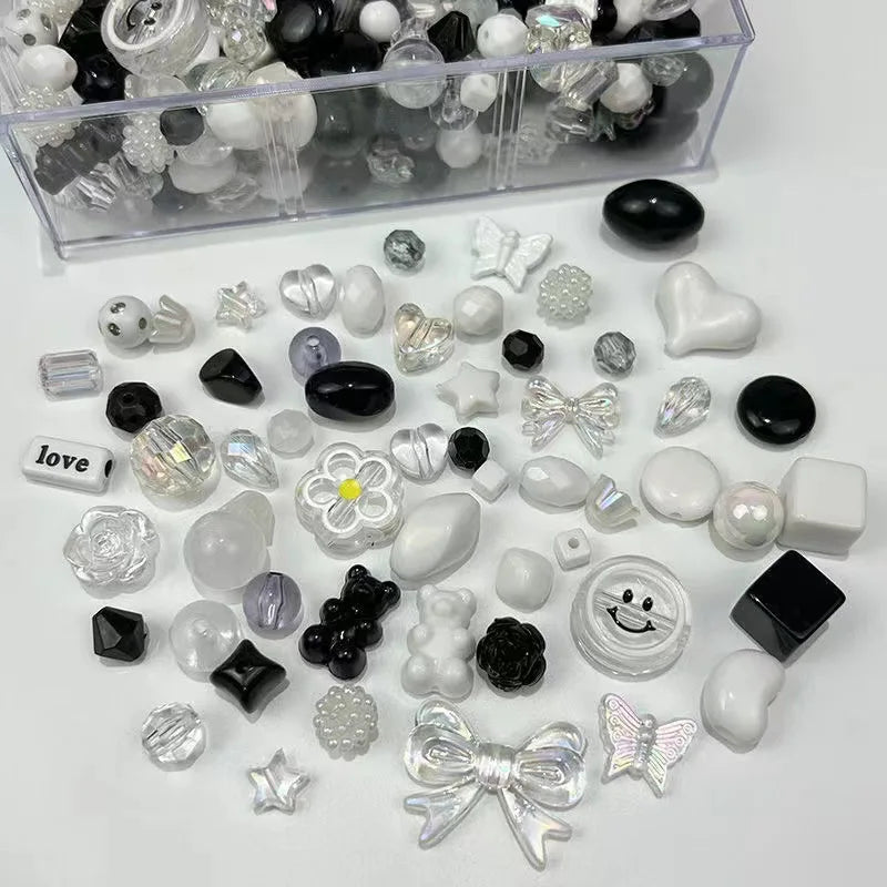 A collection of mixed clear, black, and white acrylic bow and flower beads for jewelry making.