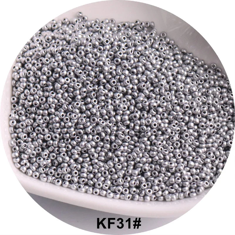 A pile of small, silver-colored glass seed beads is shown in a white dish.