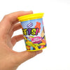 A hand holds a yellow plastic can of Spring Snake Prank, which contains colorful chips.