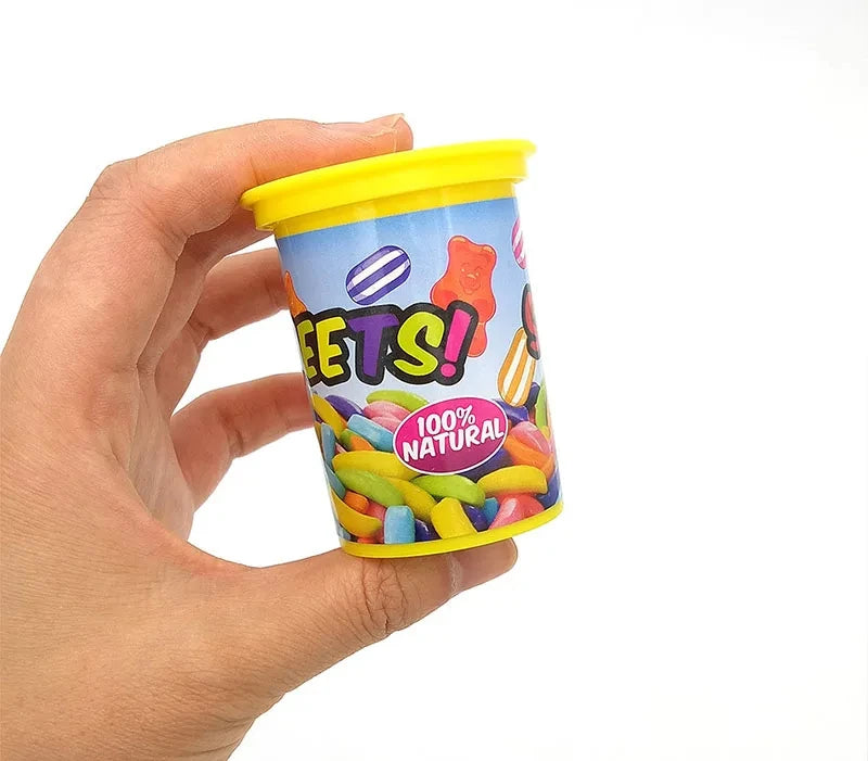 A hand holds a yellow plastic can of Spring Snake Prank, which contains colorful chips.