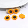 Several yellow orange sunflower charms with black centers are displayed on a white plate.
