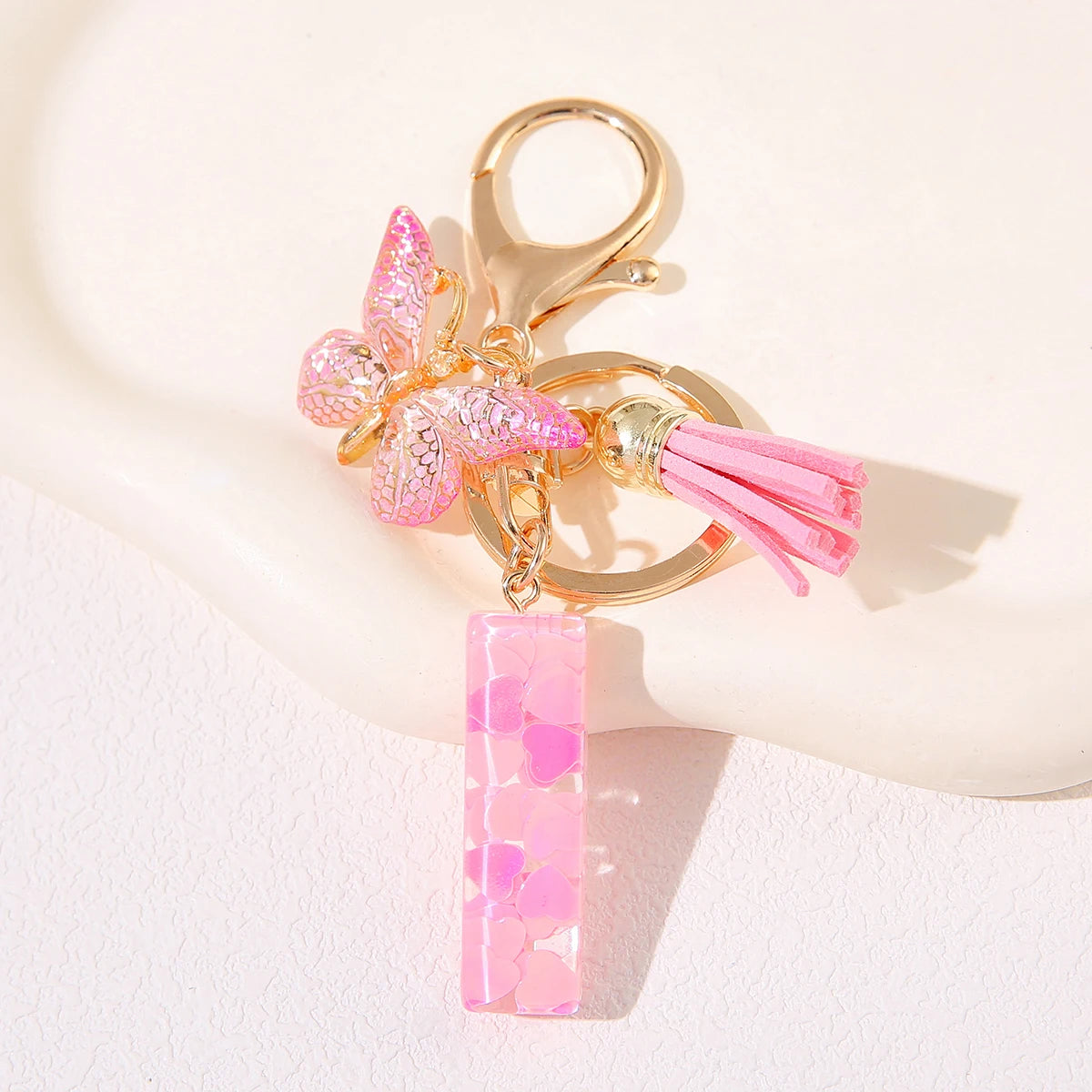 Gold heart keychain featuring a pink butterfly charm and pink tassel.