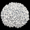 A pile of small white acrylic alphabet letter beads for jewelry making