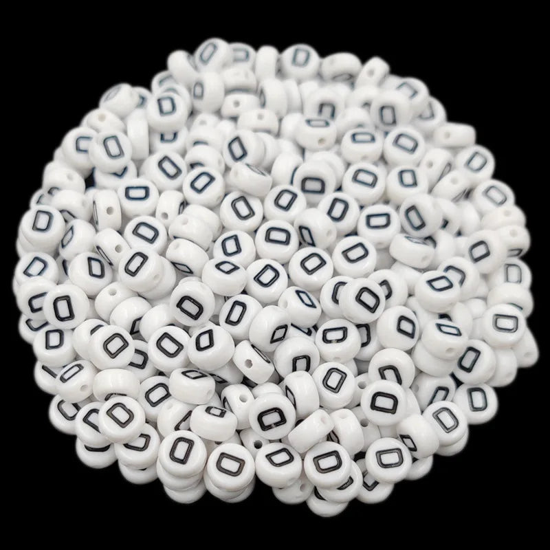 A pile of small white acrylic alphabet letter beads for jewelry making