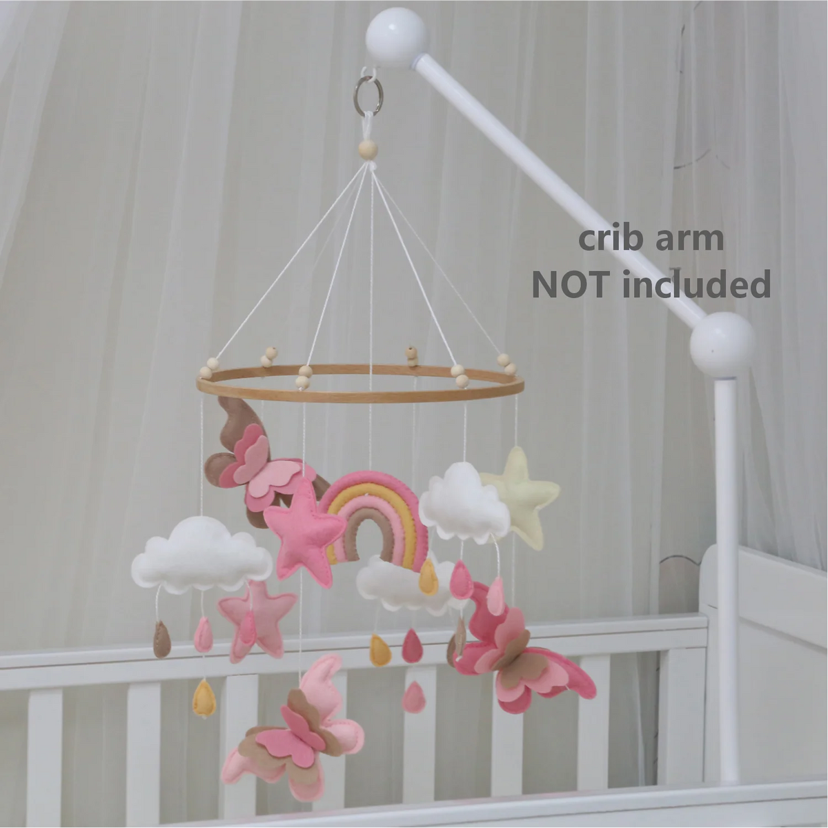 Handmade felt butterfly crib mobile with clouds and a rainbow hanging from a white crib arm.