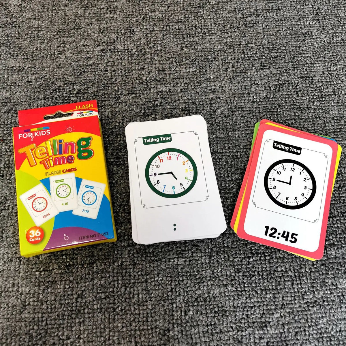 A set of Telling Time flash cards and a colorful card box are displayed on a gray fabric surface.