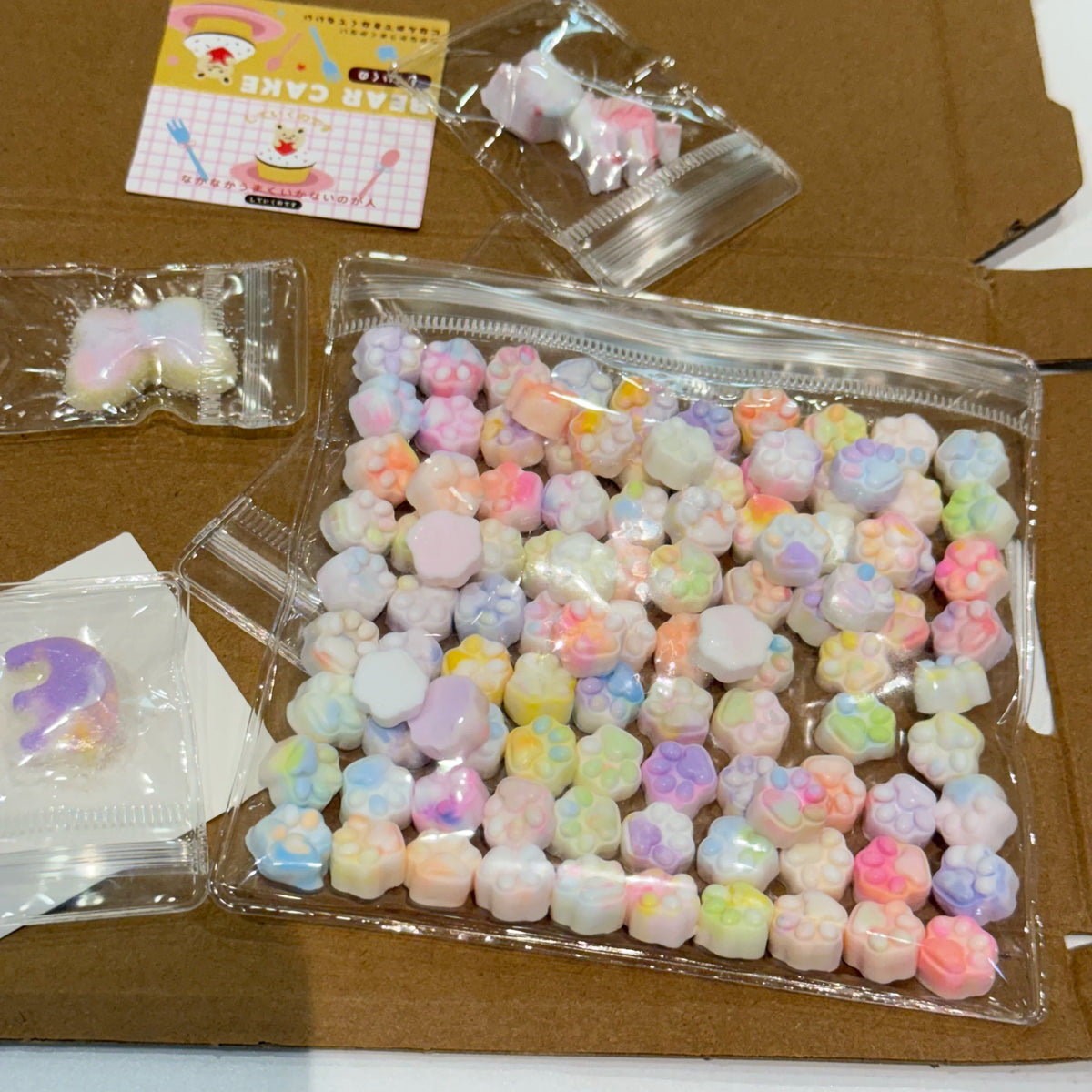 A clear plastic package filled with numerous pastel-colored squishy fidget toys shaped like cat paws.