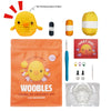 An orange bag containing a Woobles learn to crochet kit for beginners, including yarn and crochet hooks.
