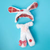A white rabbit plush doll with red plaid ears and a red bow on a light blue background.