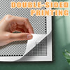 A hand is demonstrating double-sided printing on a sheet of pixel art coloring book paper.