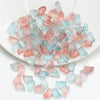 A pile of translucent pink and blue butterfly glass beads for jewelry making