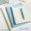 A set of three spiral notebooks in different sizes A4 B5 and A5 lying on a white surface.