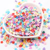 A white bowl filled with colorful polymer clay sprinkles for slime and craft decor scattered on a white surface.