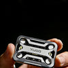 A hand holds a silver metal magnetic fidget slider device against a dark background.