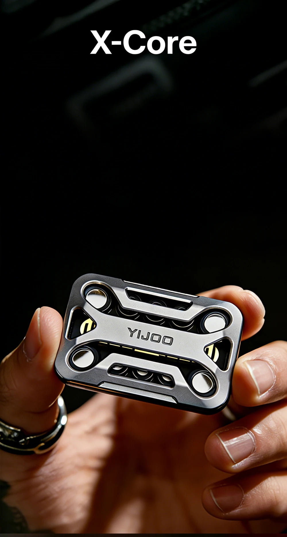 A hand holds a silver metal magnetic fidget slider device against a dark background.
