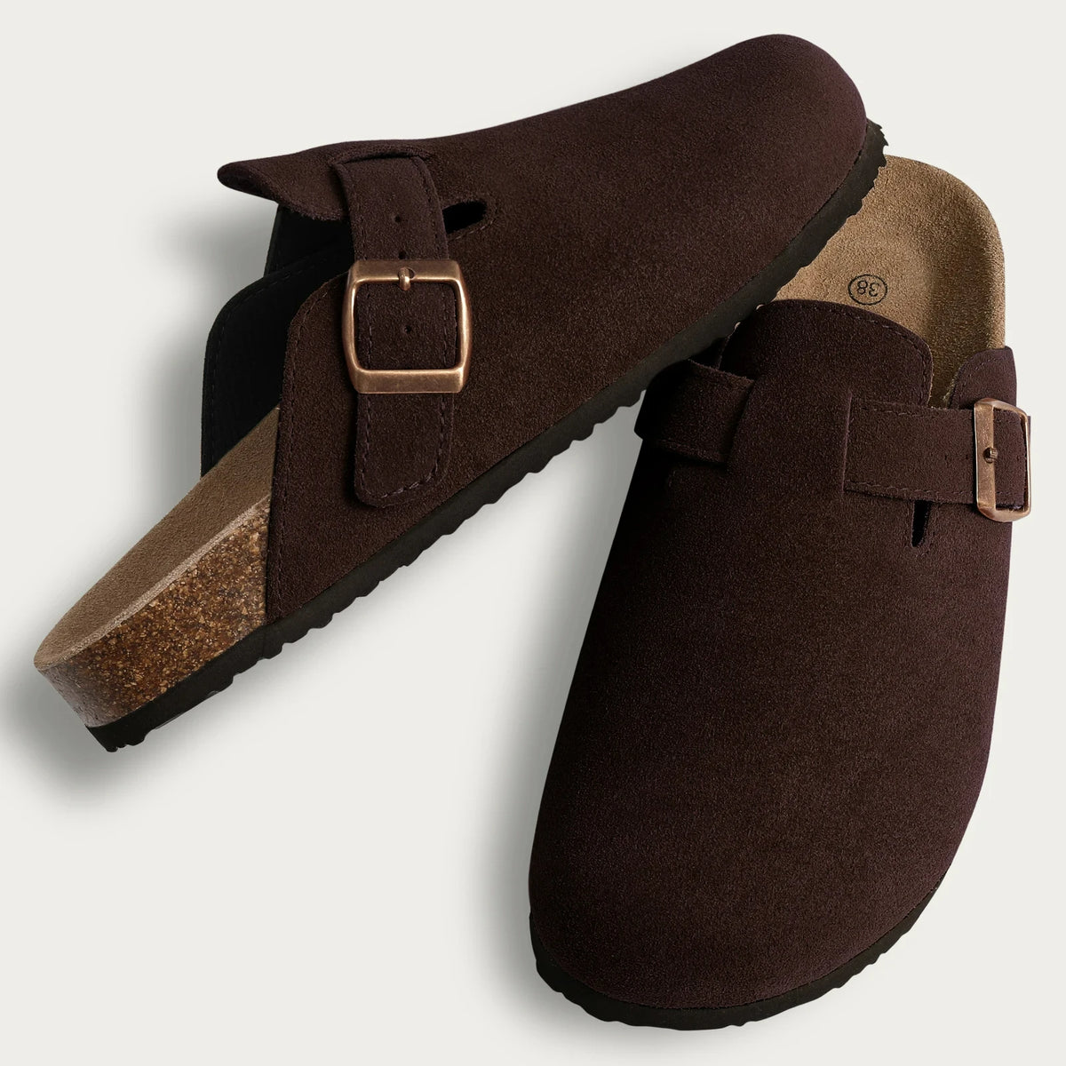 A pair of dark brown suede cork mules with leather straps and arch support.