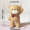 A light brown teddy bear standing decoration with a pink bow, measuring 8.8cm tall.