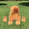 A brown capybara plush family set featuring a mama bear and four baby bears lying on green grass.