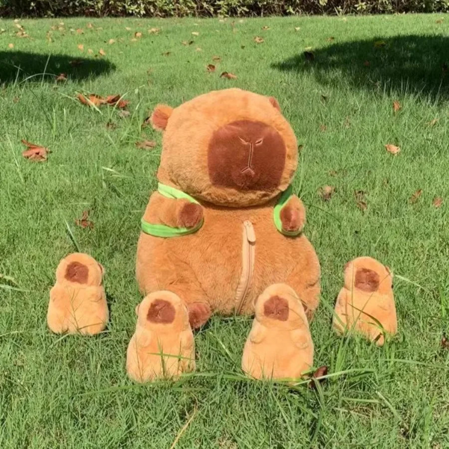 A brown capybara plush family set featuring a mama bear and four baby bears lying on green grass.