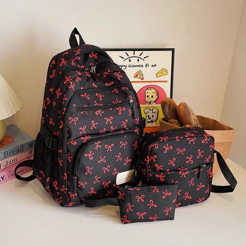 Un sac à dos noir avec motif nœud rouge et une pochette assortie sont présentés sur une surface blanche.
