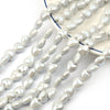 A collection of small, heart-shaped acrylic beads in white and gray are displayed on a light blue surface.