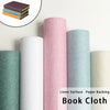 Rolls of linen book cloth in various shades including pink, mint green, and beige.