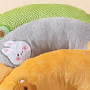A close-up of three plush U-shaped pet pillows in green, gray, and orange.