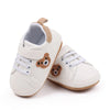 A pair of beige baby sneakers with brown bear accents for first walkers.