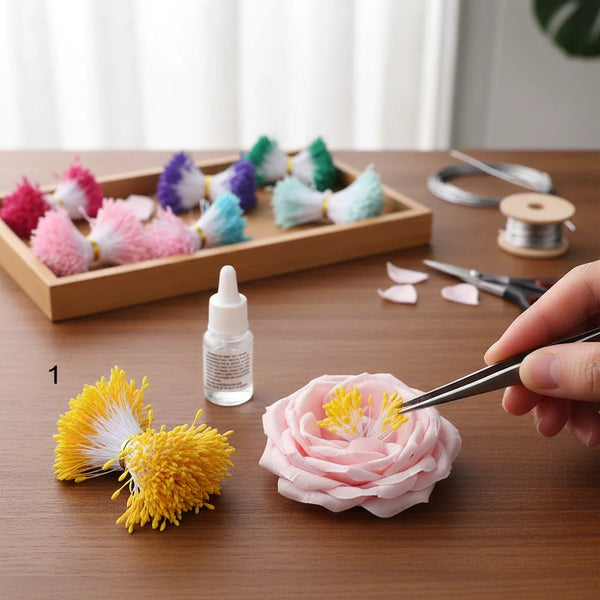 Hånd bruker pinsett til å plassere perlefinish dobbelthode blomsterstøvdragere på en rosa rose for DIY-håndverk.