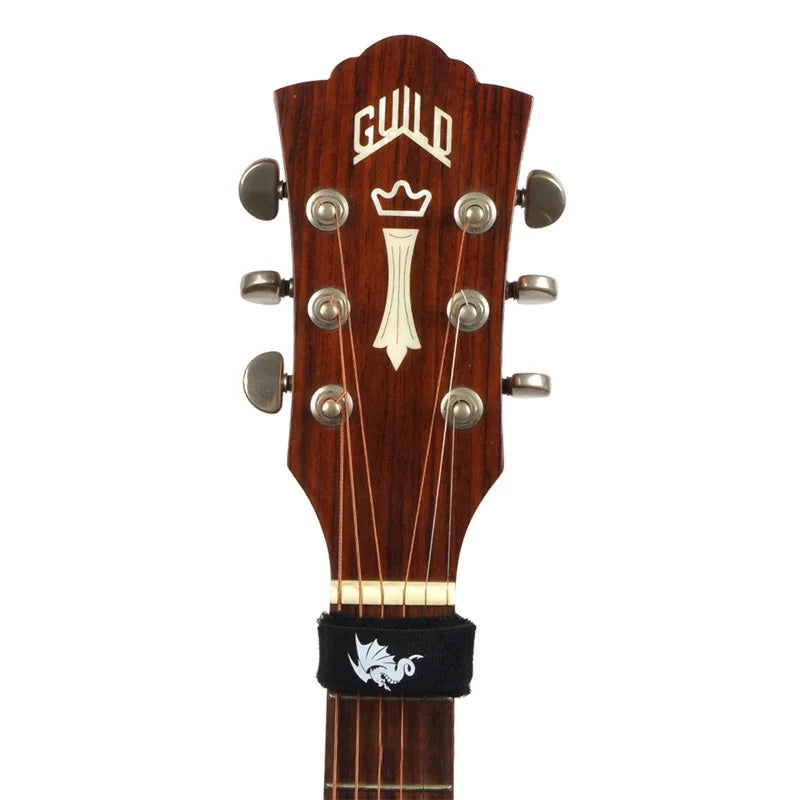 A close-up view of a guitar bridge featuring tuning pegs and a black string dampener.
