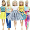 Five dolls wearing various casual outfits including tops and pants in yellow, green, blue, and pink tones