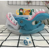 A colorful shark bite prank board game with plastic teeth and a blue body is displayed on a white checkered cloth.