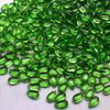 A pile of bright green water drop Czech glass beads for jewelry making.