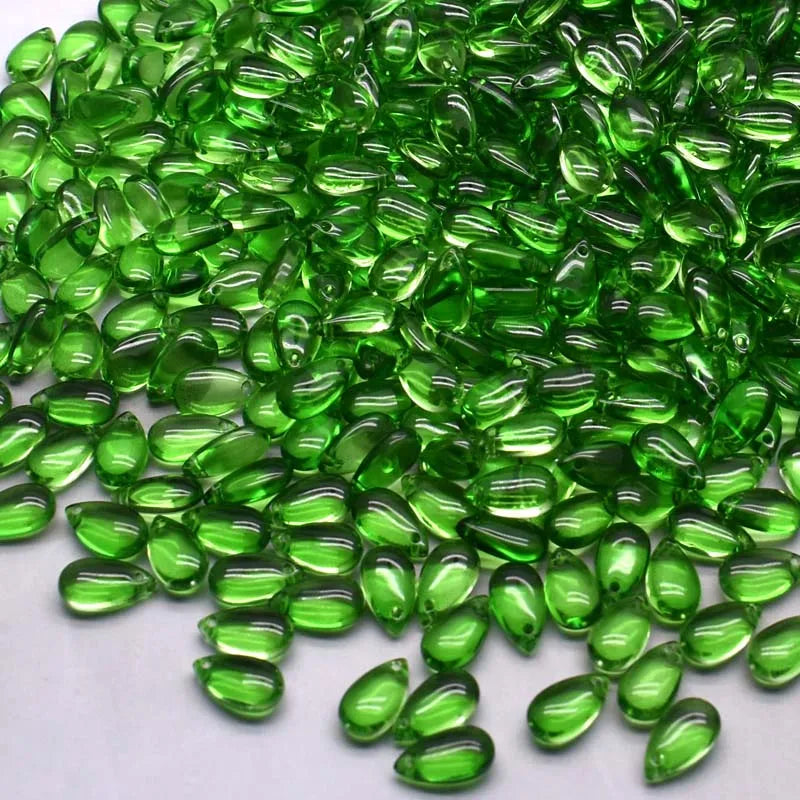 A pile of bright green water drop Czech glass beads for jewelry making.