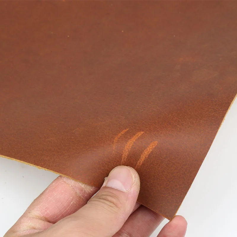 Hand holding a piece of rust red crazy horse leather hide for DIY projects