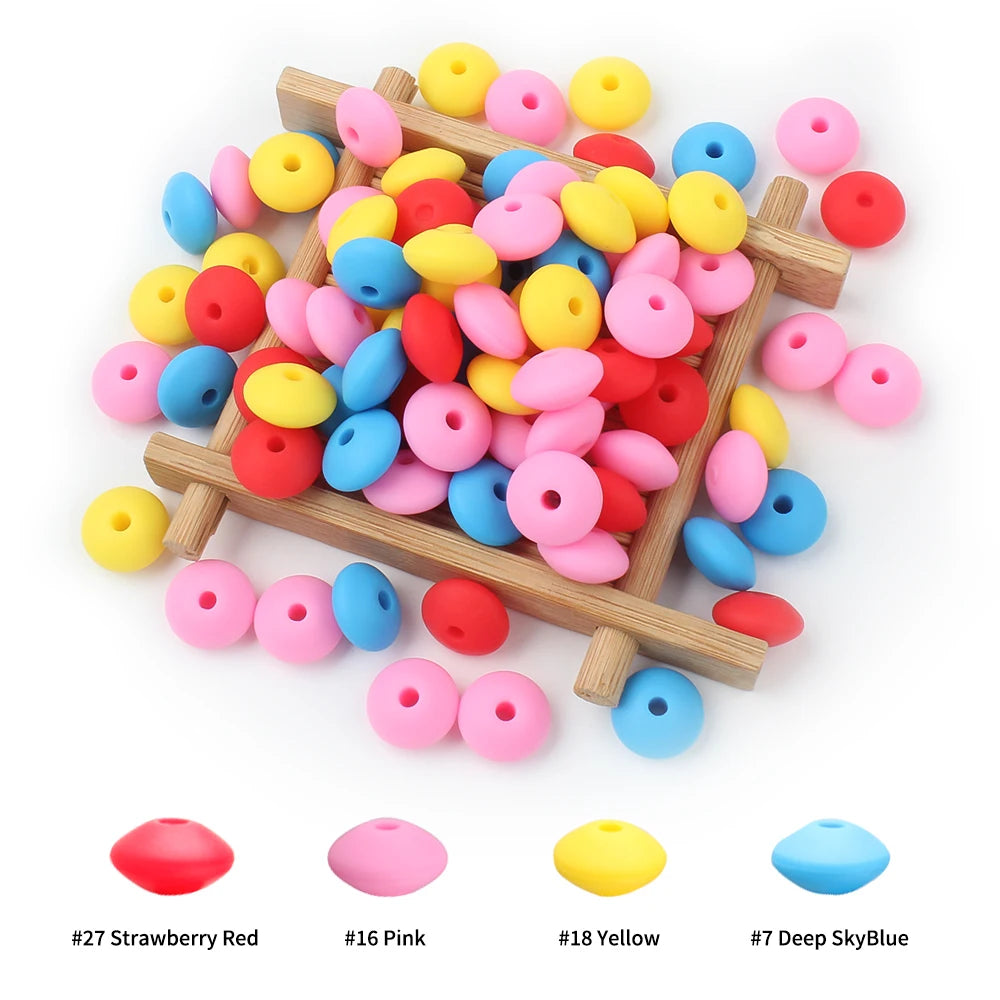A wooden tray holds various colored silicone lentil beads for jewelry making including strawberry red pink yellow and deep sk