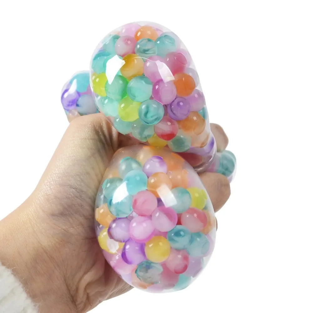 A hand holds a translucent, colorful pressure reducing fidget squishy toy filled with various colored bubbles.