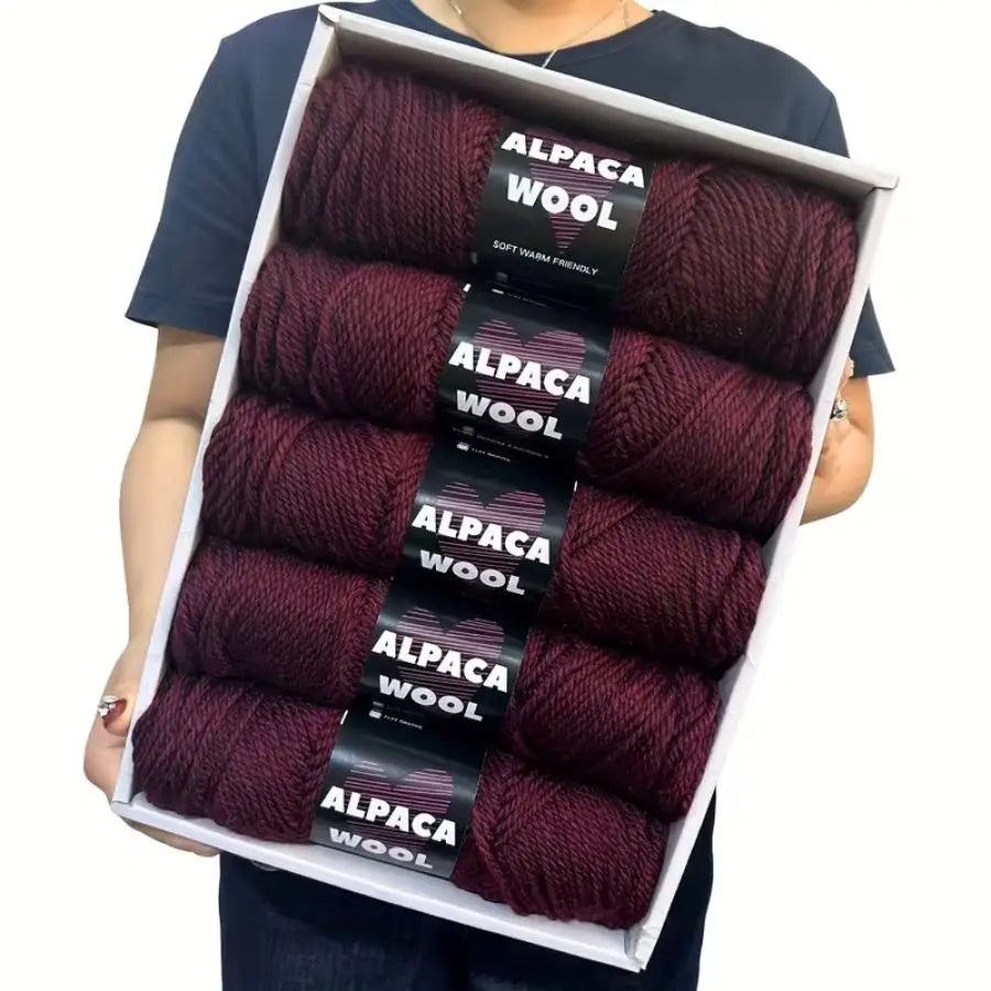 A package of five skeins of dark burgundy alpaca wool yarn for knitting and crochet projects.