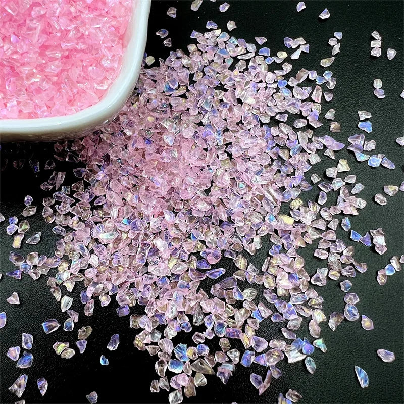 Pink crushed glass crystals scattered on a black surface.