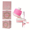Pink hand crank yarn winder device with a pink yarn ball and accessories.