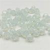 Clear faceted bicone crystal glass beads scattered on a white surface for jewelry making