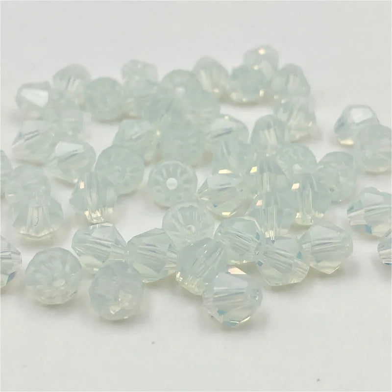 Clear faceted bicone crystal glass beads scattered on a white surface for jewelry making