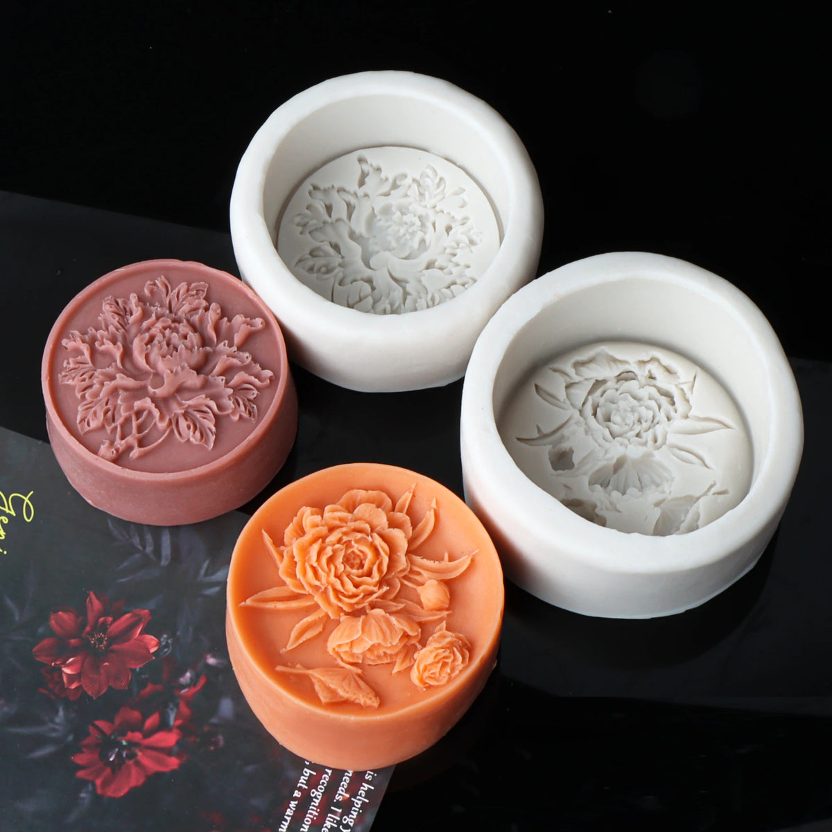 White silicone molds of peony flowers for candle, soap, and resin crafts displayed on a dark surface.